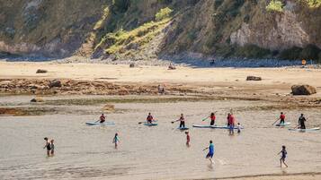A beach with people paddleboarding and walking along the shore.