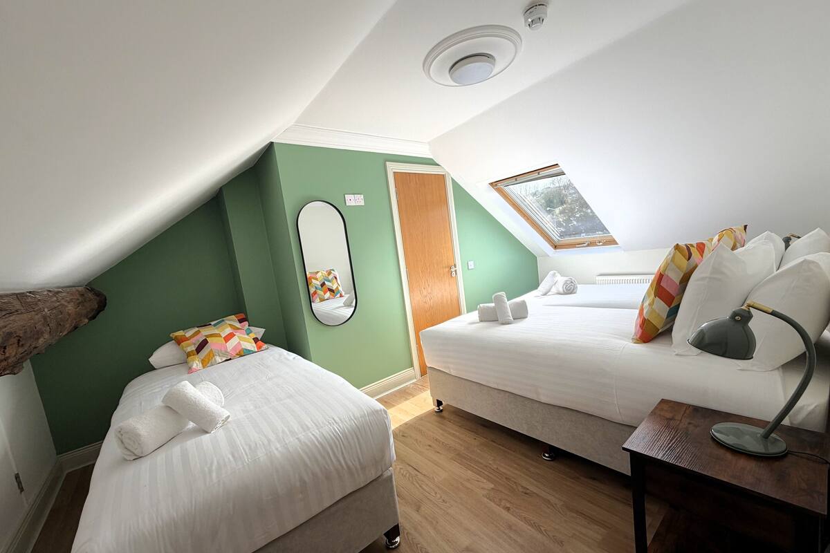 Een kamer met twee bedden, een spiegel, een bureau en een raam.