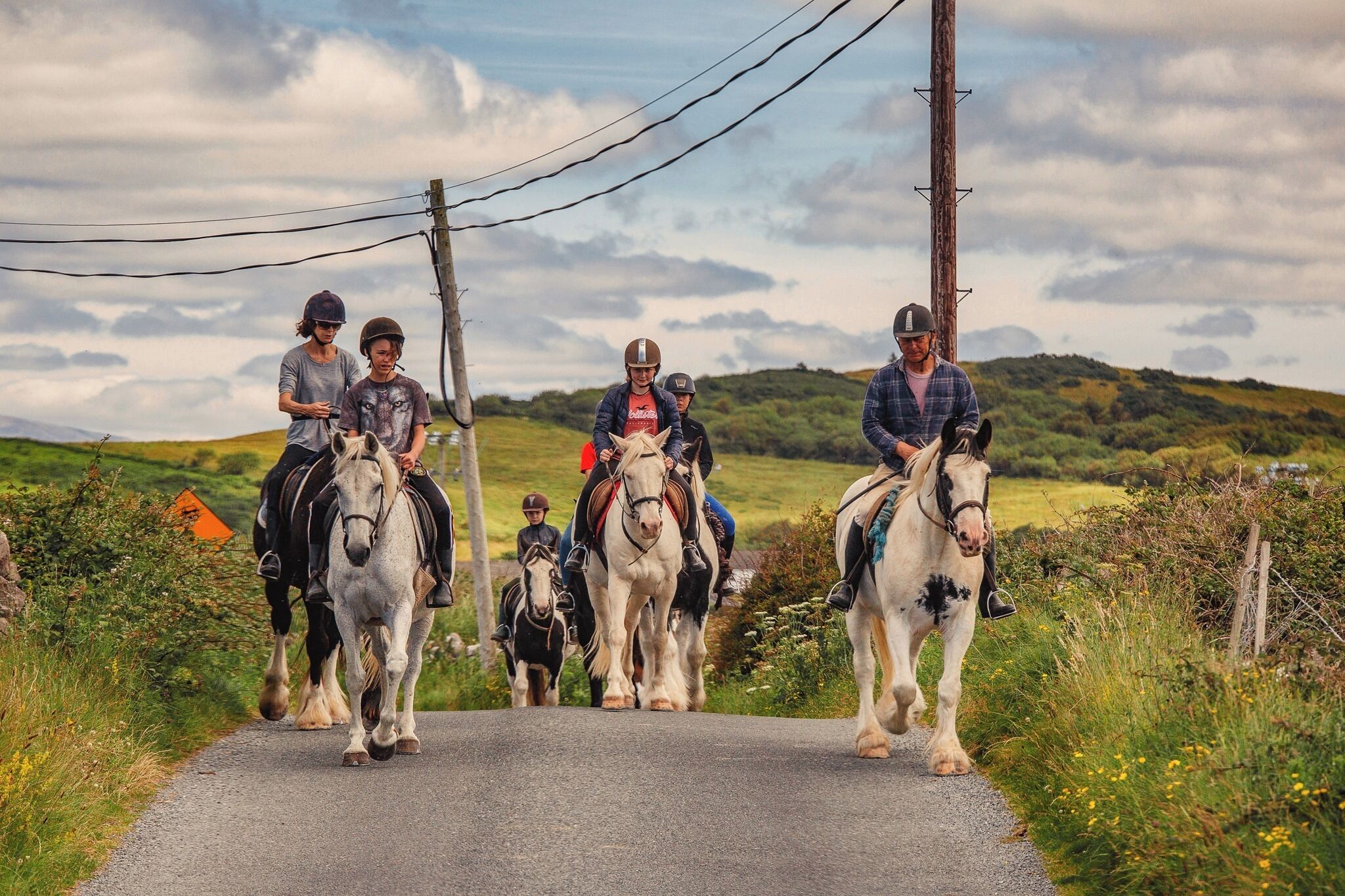 Un grupo de personas montando a caballo por un camino rural.