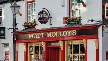 A pub named 'Matt Molloy's' with a Guinness sign, a red door, and a window displaying various items.