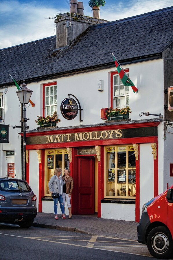 A pub named 'Matt Molloy's' with a Guinness sign, a red door, and a window displaying various items.