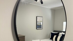 Ein Schlafzimmer mit einem Bett, einem Nachttisch, einem Spiegel und einem gerahmten Bild an der Wand.