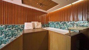 A bathroom with wooden paneling, a sink, and a shower area.