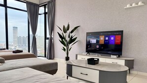 Une chambre d’hôtel moderne dotée d’une grande télévision, de deux lits, d’une plante en pot et offrant une vue sur la ville.
