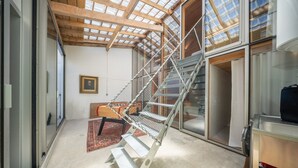 A modern interior with a metal spiral staircase, large windows, and a visible door. - Cabane Cala – Heart of Arcachon & Beaches Within Walking Distance (Arcachon)