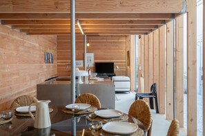A wooden interior with a dining area, a TV, and a sofa. - Cabane Cala – Heart of Arcachon & Beaches Within Walking Distance (Arcachon)