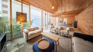 A modern interior with wooden walls, large windows, a dining area, and a TV. - Cabane Cala – Heart of Arcachon & Beaches Within Walking Distance (Arcachon)