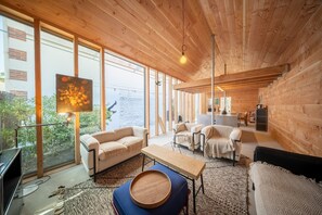 A modern interior with wooden walls, large windows, a dining area, and a TV. - Cabane Cala – Heart of Arcachon & Beaches Within Walking Distance (Arcachon)