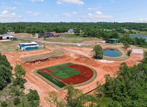 Vue aérienne d’un terrain de sport comprenant un terrain de baseball, des bâtiments environnants et une étendue d’eau.