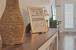 Een lijst met een welkomstbord, een gevlochten mand en een lamp op een houten tafel.