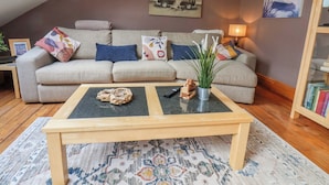 Un salon confortable avec un canapé, une table basse, une lampe et une bibliothèque.