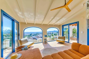 Ein geräumiger Balkon mit einem modernen Deckenventilator, großen Fenstern und Blick auf die Stadtlandschaft.