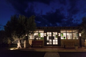 A building with a glass facade, a wooden bench, and a potted plant in front. - Muses Hammamet Villa 5 Bedrooms (Hammamet)