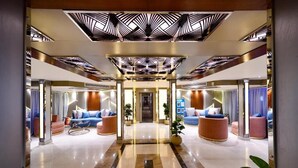 A hotel lobby with a central hallway, seating areas on either side, and a modern ceiling design. - MS Nile Treasure Cruise (Luxor)