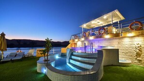 A pool area with steps leading into the water, lounge chairs, and a statue. - MS Nile Treasure Cruise (Luxor)