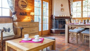 Ein gemütliches Blockhaus-Interieur mit Holzwänden, Kamin, Essbereich und Küche.