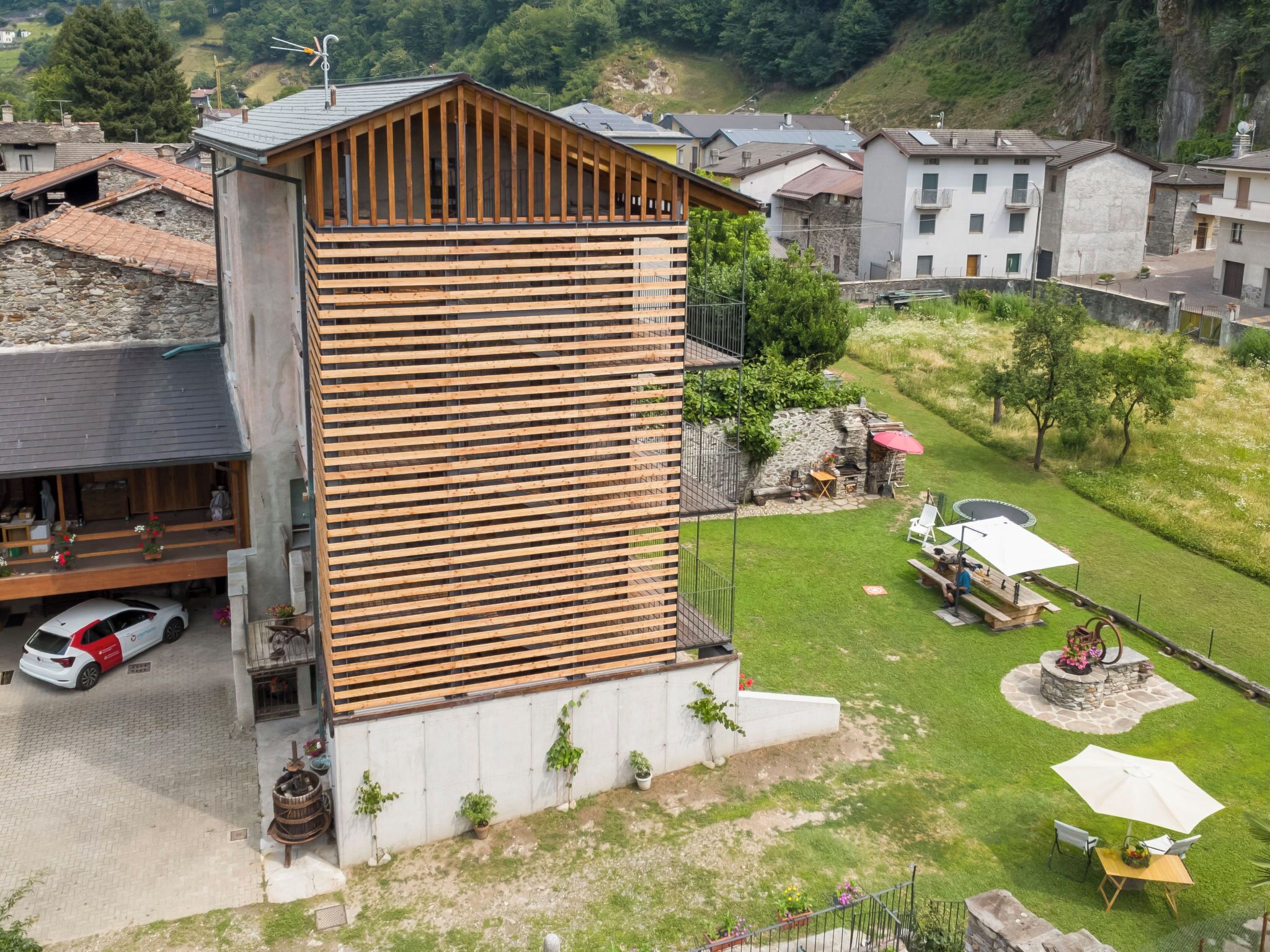 Un bâtiment moderne doté d’une façade en bois, d’un balcon et d’une pelouse bien entretenue avec des sièges d’extérieur.