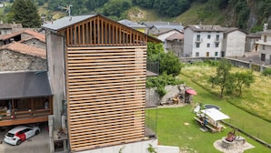 Ein modernes Gebäude mit Holzfassade, einem Balkon und einem gepflegten Rasen mit Gartenmöbeln.
