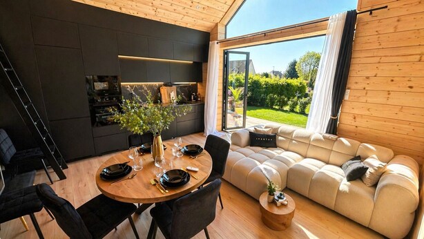 Un interno moderno con un tavolo da pranzo per quattro persone, un divano e un angolo cottura con una grande finestra.