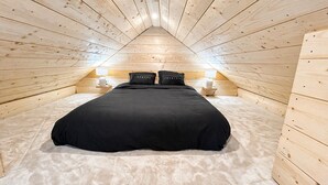 Una stanza con rivestimento in legno, un letto, due comodini e due lampade.