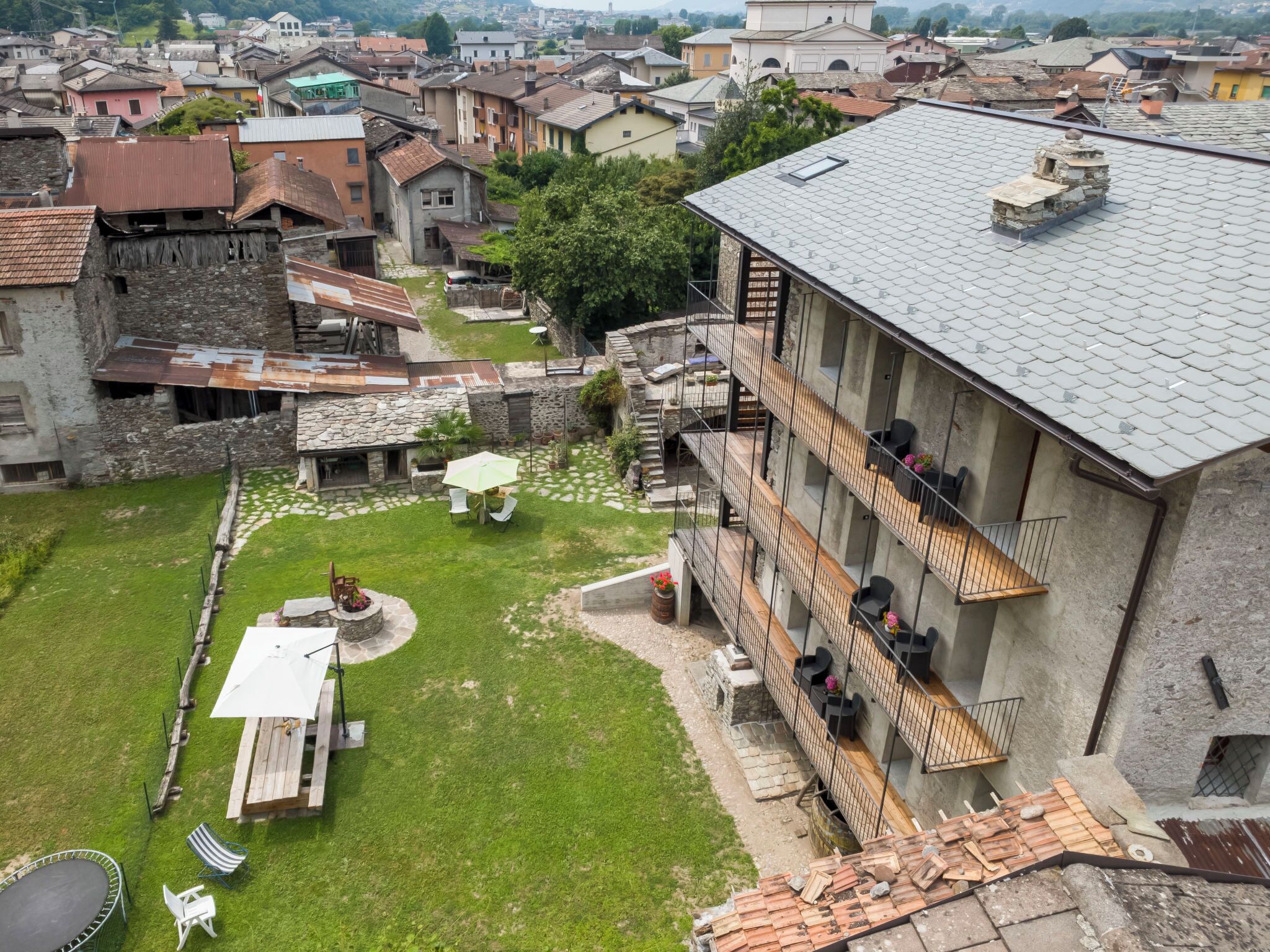 Une cour comprenant un espace repas, des sièges extérieurs et un bâtiment doté d’un balcon.