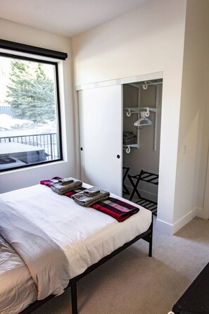 Ein Schlafzimmer mit Bett, Fenster, Kleiderschrank und Stuhl.