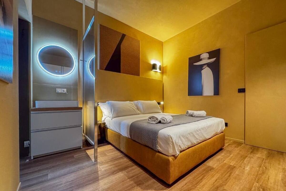 Een moderne hotelkamer met een bed, nachtkastje, een wandlamp en een schilderij.