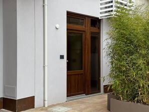 Ein modernes Gebäude mit einer großen Holztür, einer weißen Wand und einem Blumentopf.