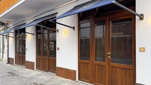 A building with a covered entrance, wooden doors, and a tiled walkway. - Blu Rooms - Room to Rest (Civitanova Marche)