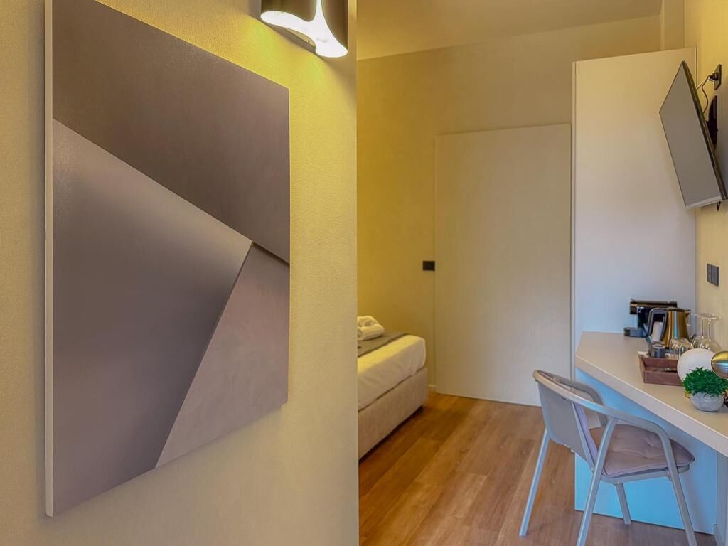 Ein modernes Zimmer mit einem Bett, einem Schreibtisch mit Stuhl und einem großen abstrakten Gemälde an der Wand.