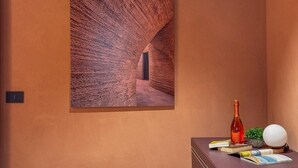 A room with a textured wall, a bottle, a globe, and books on a table. - Blu Rooms - Room to Rest (Civitanova Marche)