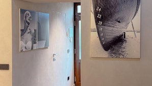 A hallway with two framed artworks on the walls, one depicting a figure with a bow and the other a boat with numbers. - Blu Rooms - Room to Rest (Civitanova Marche)