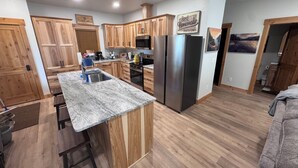Una cocina moderna con armarios de madera, encimera de granito, electrodomésticos de acero inoxidable y una zona de bar.
