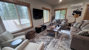 Una sala de estar con sofá, sillón, mesa de centro y televisor.