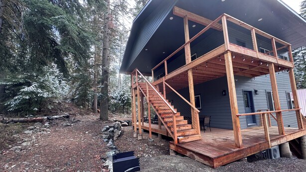 Una cabaña con escalera de madera, terraza y techo de metal.