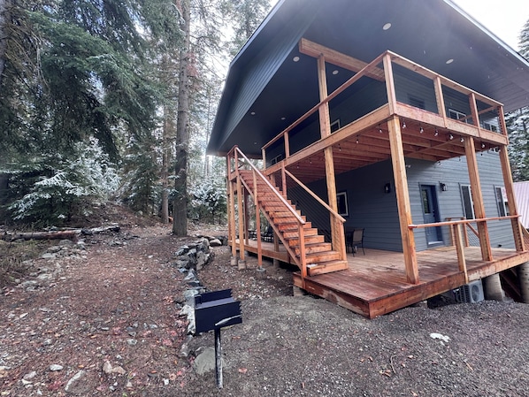 A cabin with a wooden staircase, a deck, and a metal roof.