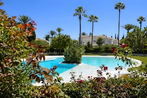 A swimming pool surrounded by lush greenery and tall palm trees. - RDR549 - Charming 4 BR in Exclusive Camoján Blanco (Marbella)