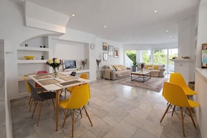 A modern living room with a dining area, featuring a large table, yellow chairs, and a sofa set. - RDR549 - Charming 4 BR in Exclusive Camoján Blanco (Marbella)