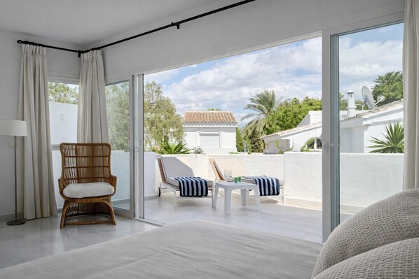 A modern hotel room with a large sliding glass door leading to an outdoor balcony with a view of the surrounding area. - RDR549 - Charming 4 BR in Exclusive Camoján Blanco (Marbella)