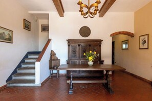 Ein geräumiges Zimmer mit Holztisch, Treppe und einer dekorativen Deckenleuchte.