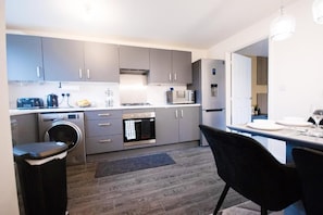 Una cocina moderna con armarios grises, horno empotrado, microondas y lavadora.