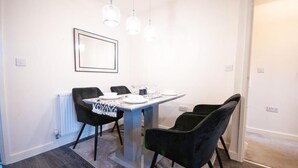 A dining area with a table, chairs, pendant lights, and a framed picture on the wall. - Spacious Luxurious Serviced Accommodation 2 (Coventry)