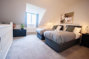Un dormitorio con dos camas, un radiador, una ventana y un cuadro en la pared.