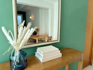 A wooden console table with a vase of pampas grass and a stack of books. - Sea Sun & Pool - Charming 1BR Apt (San Juan)