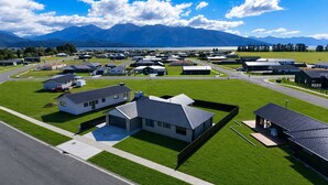 A residential area with modern houses, a road, and mountains in the background. - Fiordland Gateway by Aotearoa Escapes (Te Anau)