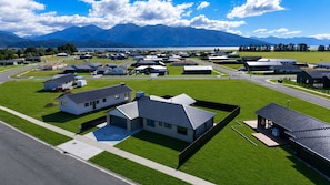Un barrio residencial con casas modernas, una carretera y montañas al fondo.