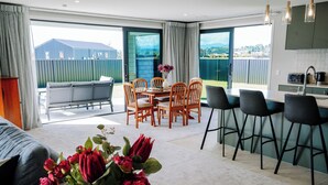 A modern interior with a dining area, kitchen, and a view of the outdoors. - Fiordland Gateway by Aotearoa Escapes (Te Anau)