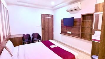 Un dormitorio con cama, ventilador de techo, equipo de aire acondicionado, televisor y armario de madera.