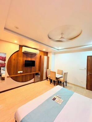 Ein Hotelzimmer mit Bett, Schreibtisch, Stuhl, Fernseher und Klimaanlage.