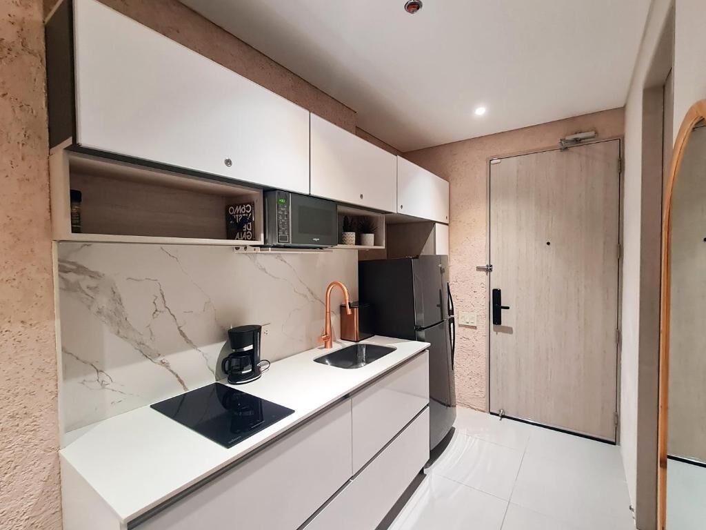 A compact kitchen with a microwave, coffee maker, sink, and a refrigerator.